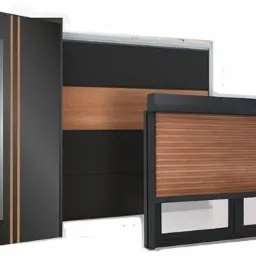 Otwarta czarna nowoczesna drzwi wejściowe z pionowymi paskami dekoracyjnymi, obok zamknięta drewniana roleta zewnętrzna z czarną ramą oraz fragment czarnej ściany z drewnianym panelem w tle.