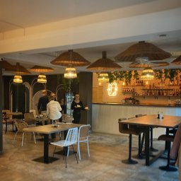 Oliwia Kalandyk Architektura Wnętrz - Wnętrze restauracji z rattanowymi lampami, barem z neonowym logo i stolikami dla gości