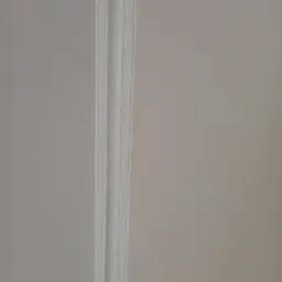 Fragment ściany z listwą dekoracyjną pomalowaną na biało, sąsiadującą z ścianą w odcieniu beżu.