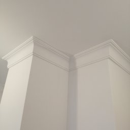 Sławomir Przybylski - Białe, ozdobne listwy przysufitowe na styku ściany i sufitu, widok z dołu, minimalistyczny design.