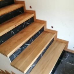 Sławomir Przybylski - Schody z drewnianymi stopniami i okładziną z czarnego marmuru z białymi żyłami, widok z dołu na górę.