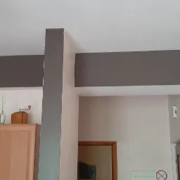 Pomieszczenie po odświeżeniu: szare pasy na ścianach i suficie, widoczna szafka kuchenna z dekoracjami.