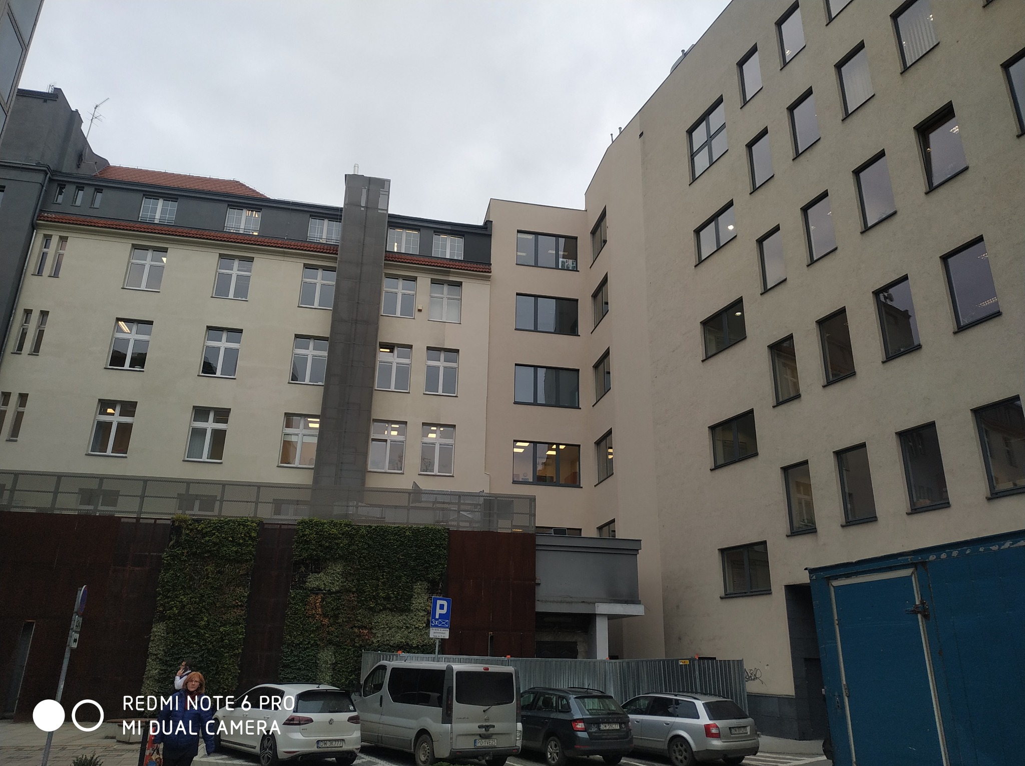 Budynek Urzędu Miejskiego we Wrocławiu po naprawie po pożarze, widoczne fragmenty elewacji, okna, parking i roślinność na elewacji