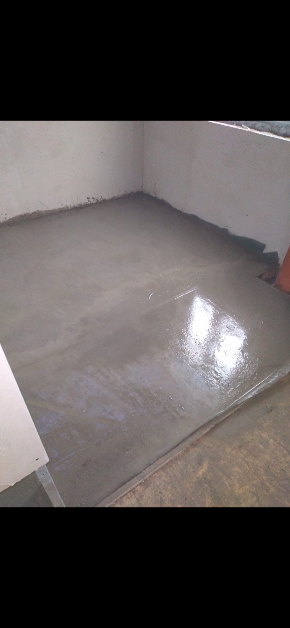 Świeżo wylana, mokra wylewka samopoziomująca w rogu pomieszczenia, widoczne ślady po wałku odpowietrzającym.