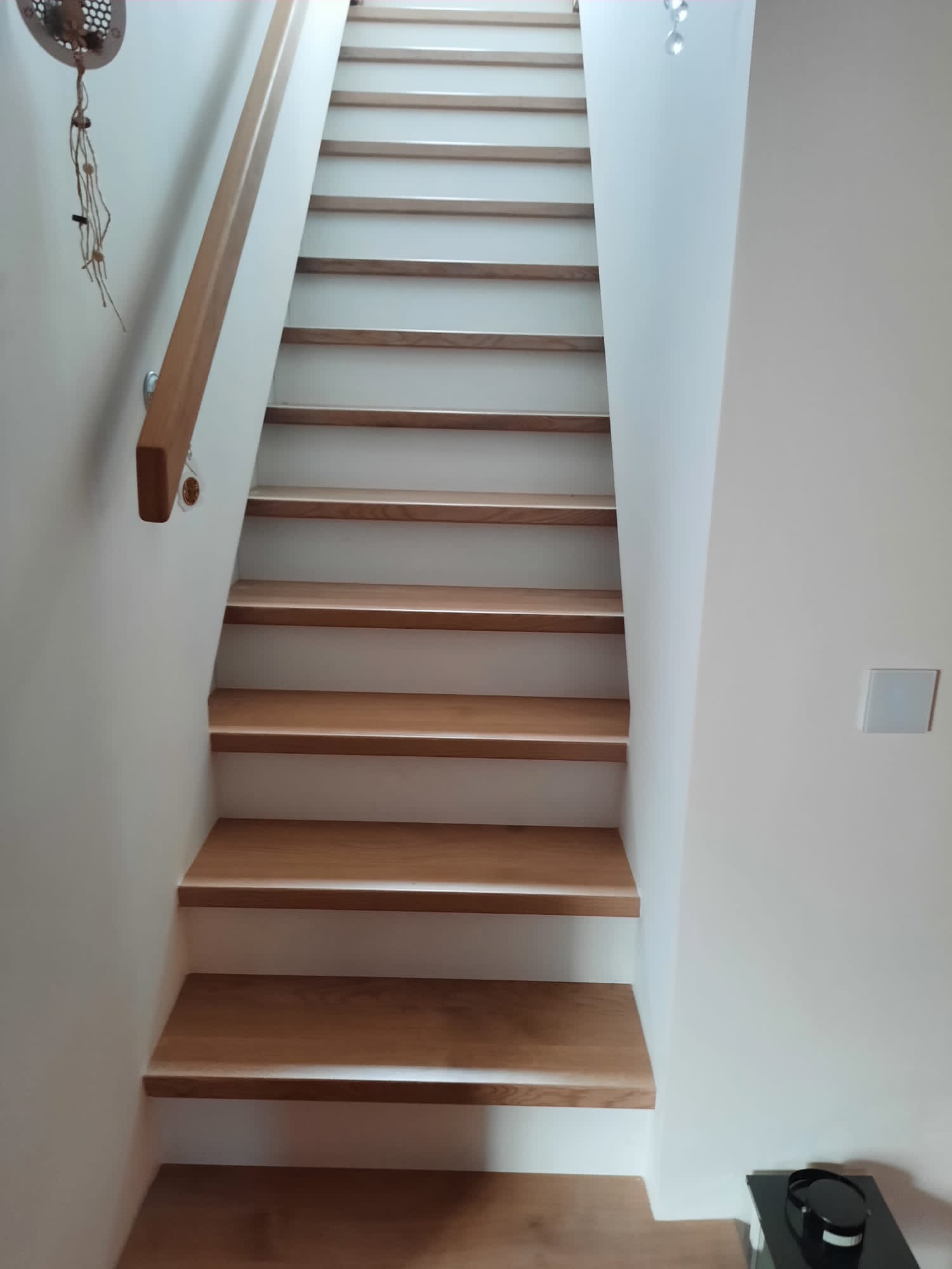 Nowoczesne drewniane schody z jasnymi stopniami i drewnianą poręczą, widok z dołu, minimalistyczny design.