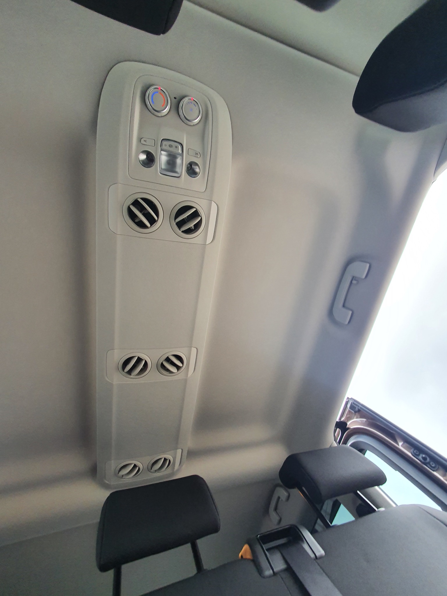 Wnętrze samochodu z widocznym panelem sterowania klimatyzacją dla pasażerów z tyłu oraz regulowanymi nawiewami, skierowanymi w dół