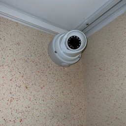 Eye'sCAM - Kamera kopułkowa monitoringu, zamontowana w rogu pomieszczenia z beżowymi ścianami w cętki, widoczna od dołu, z bliska.