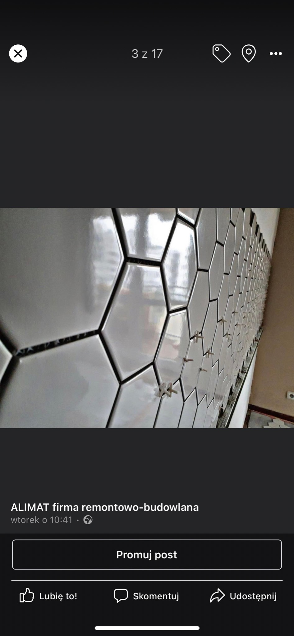 Układanie heksagonalnych, błyszczących, białych płytek na ścianie w Brzesku; widoczne krzyżyki dystansowe między płytkami.