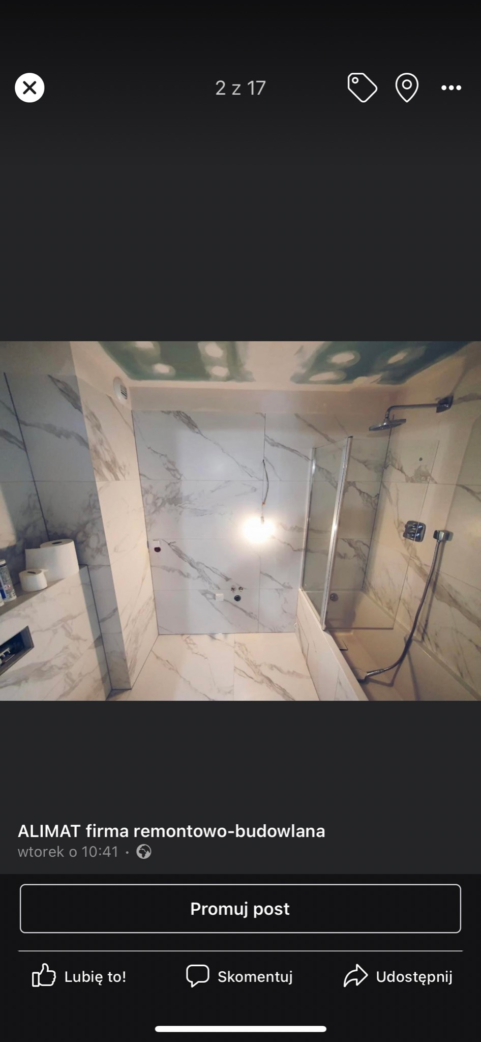 Nowoczesna łazienka w trakcie remontu, widoczne białe płytki imitujące marmur, kabina prysznicowa ze szklaną ścianką oraz sufit z płyt kartonowo-gipsowych przed szpachlowaniem.