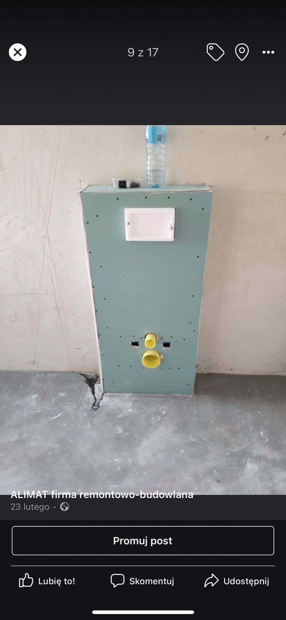 Konstrukcja z płyty karton gips, z widocznymi żółtymi rurami instalacji wodnej, białą puszką elektryczną i butelką wody na górze, w trakcie prac wykończeniowych w łazience.