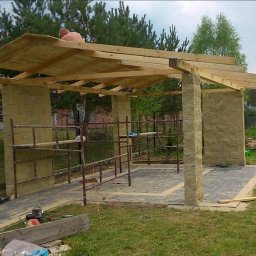 Mar-Bud usługi budowlane - Budowa altany z kamiennymi filarami i drewnianym dachem w trakcie montażu, widoczne rusztowania i narzędzia na ziemi.