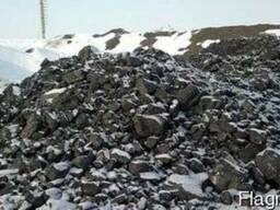 Góra czarnego węgla kamiennego pokryta śniegiem, na tle zaśnieżonego krajobrazu.