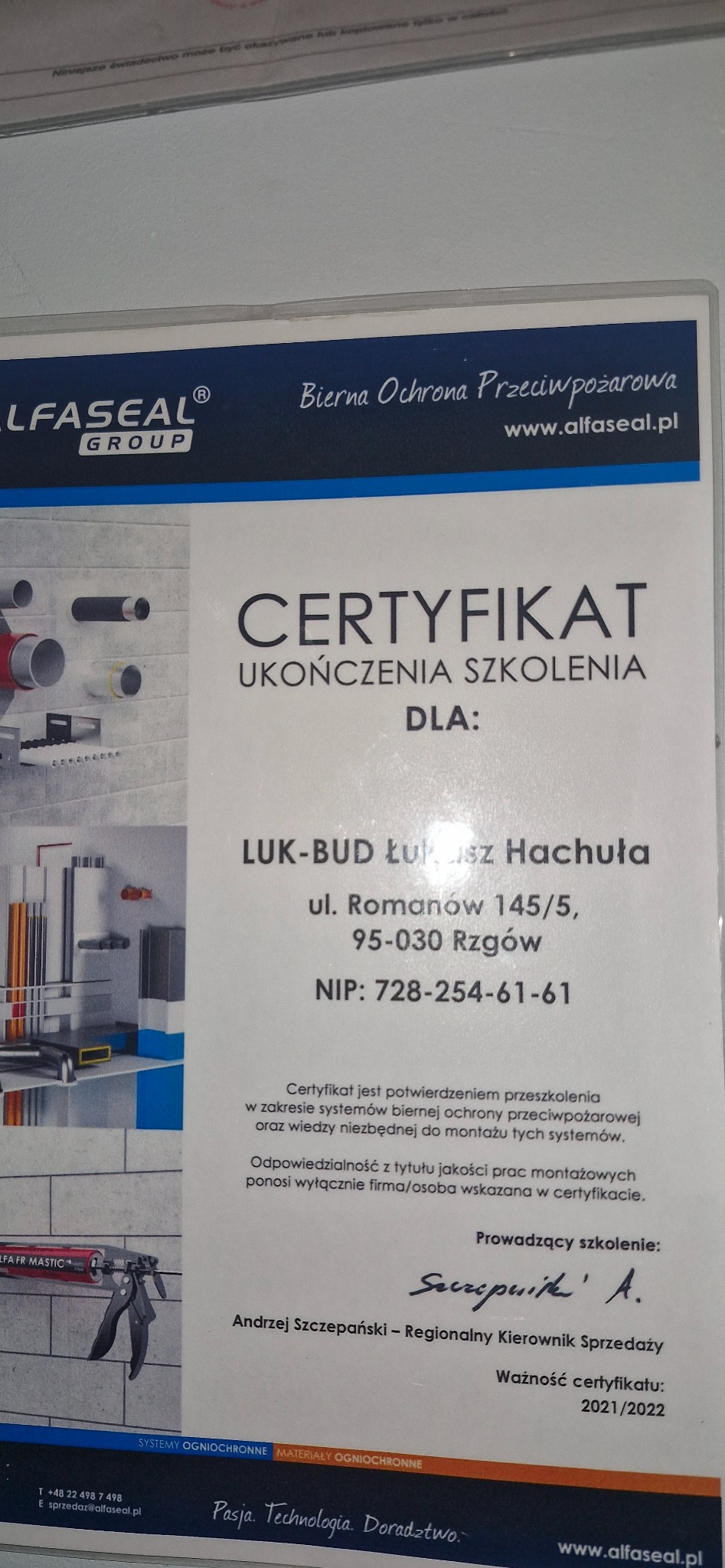 Certyfikat ukończenia szkolenia firmy LUK-BUD w zakresie systemów biernej ochrony przeciwpożarowej, z wizualizacją montażu rur i narzędzi, wydany przez Alfa Seal Group, ważny w latach 2021-2022.