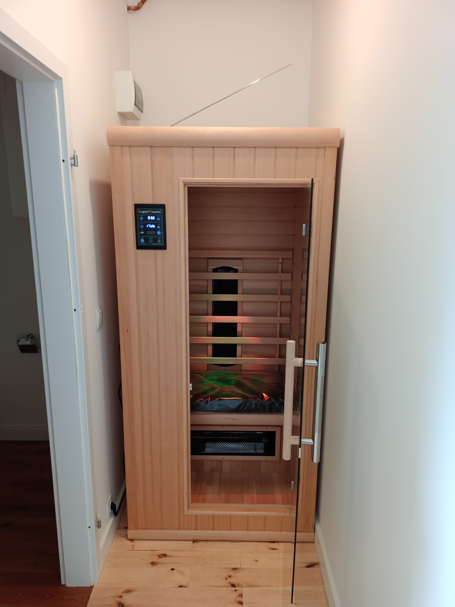 Zamontowana sauna infrared z drewnianymi panelami i szklanymi drzwiami w pomieszczeniu w Pastuchowie, widoczny panel sterowania i oświetlenie wewnątrz.