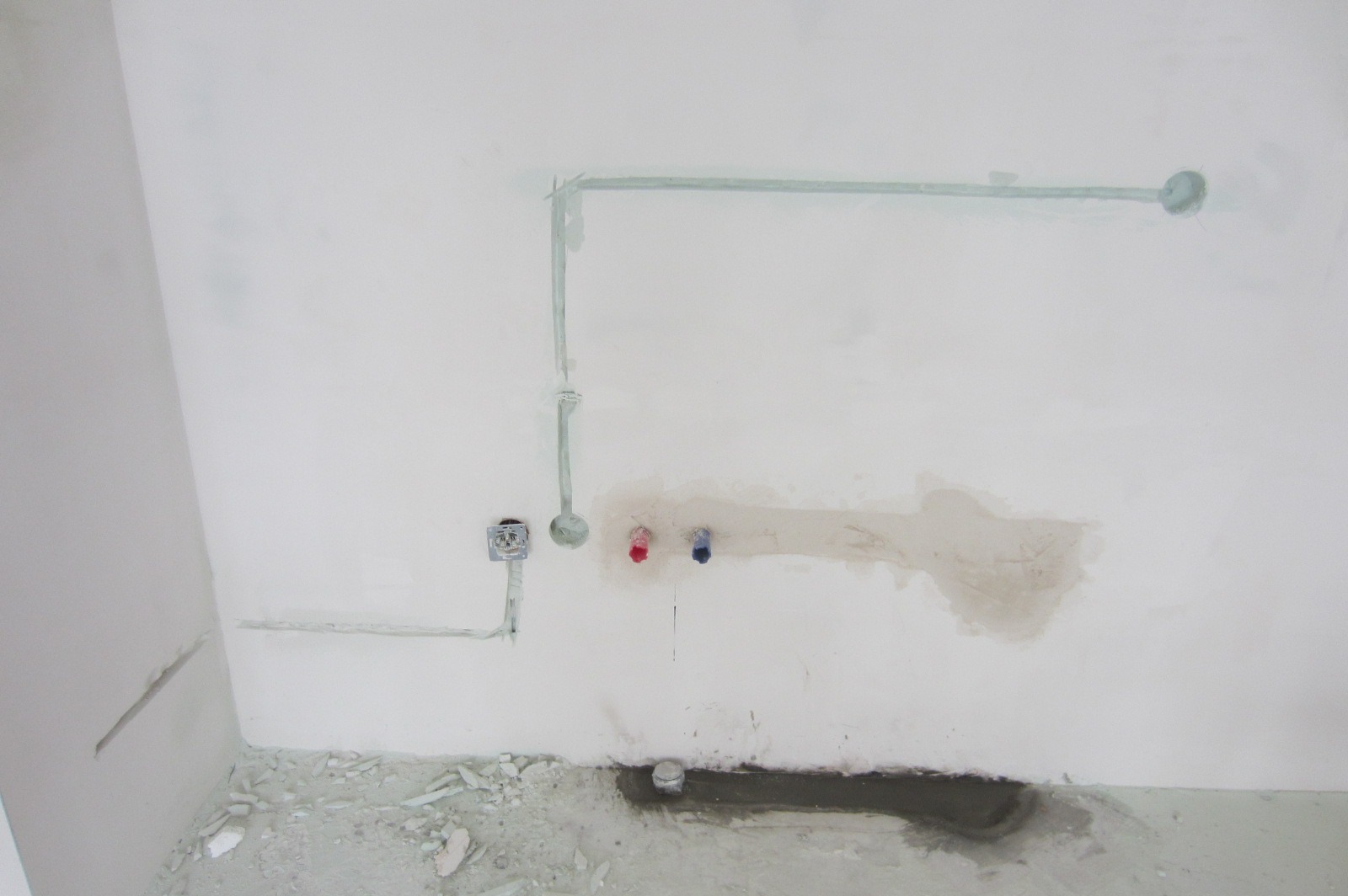 Przygotowanie instalacji elektrycznej i hydraulicznej w surowym wnętrzu: poprowadzone kable w listwach, wystające rury ciepłej i zimnej wody, przygotowane odprowadzenie kanalizacyjne w podłodze...