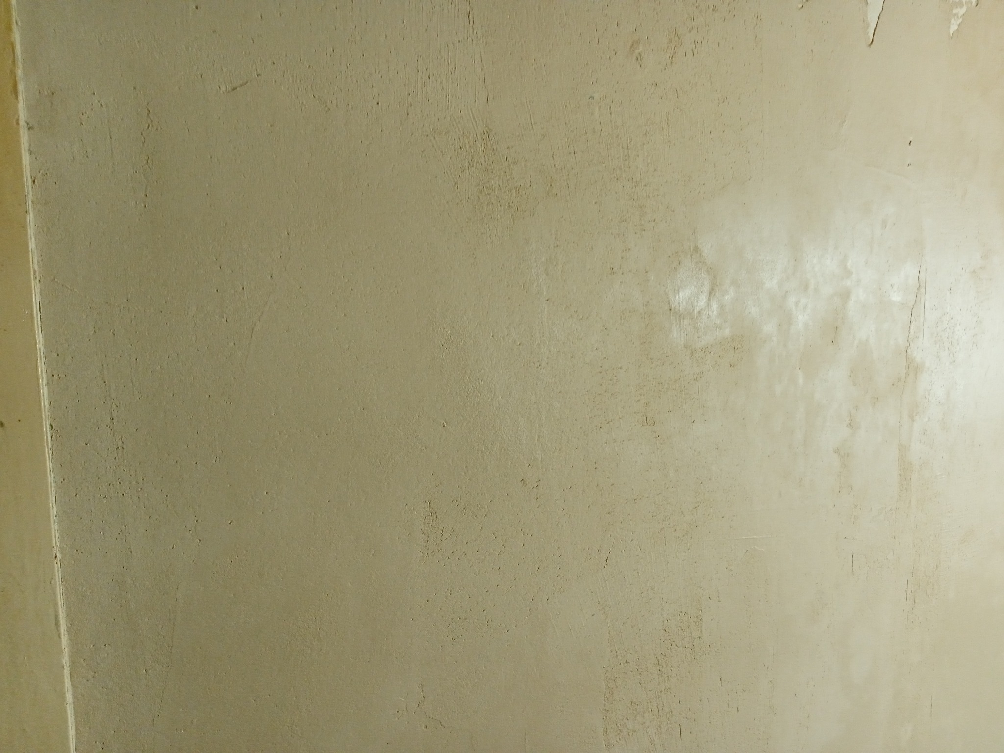 Ściana po szpachlowaniu, widoczne nierówności i ślady po narzędziach, przygotowana do dalszych prac wykończeniowych.