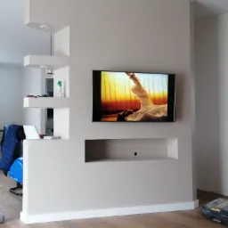 Ścianka działowa z płyt karton-gips z wnękami i zamontowanym telewizorem w Husowie, świeżo po malowaniu, z widoczną skrzynką narzędziową na podłodze.