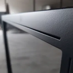 Detale spawu na ramie z czarnego metalu, widoczna faktura powierzchni i szczelina dylatacyjna, tło rozmyte.