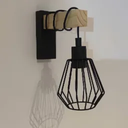 Czarny kinkiet z drewnianym elementem, rzucający wyraźny cień na jasną ścianę.