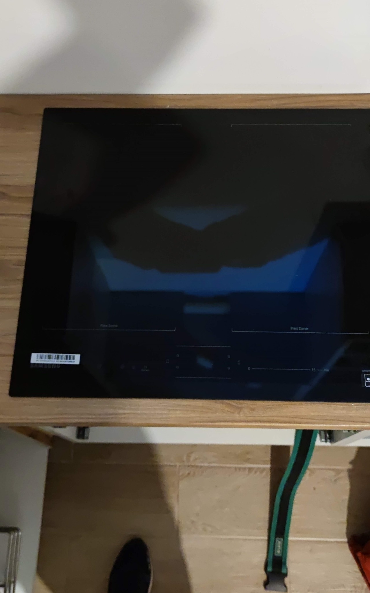 Czarna płyta indukcyjna Samsung zamontowana w drewnianym blacie kuchennym, widoczne panele sterowania i oznaczenia stref grzewczych.