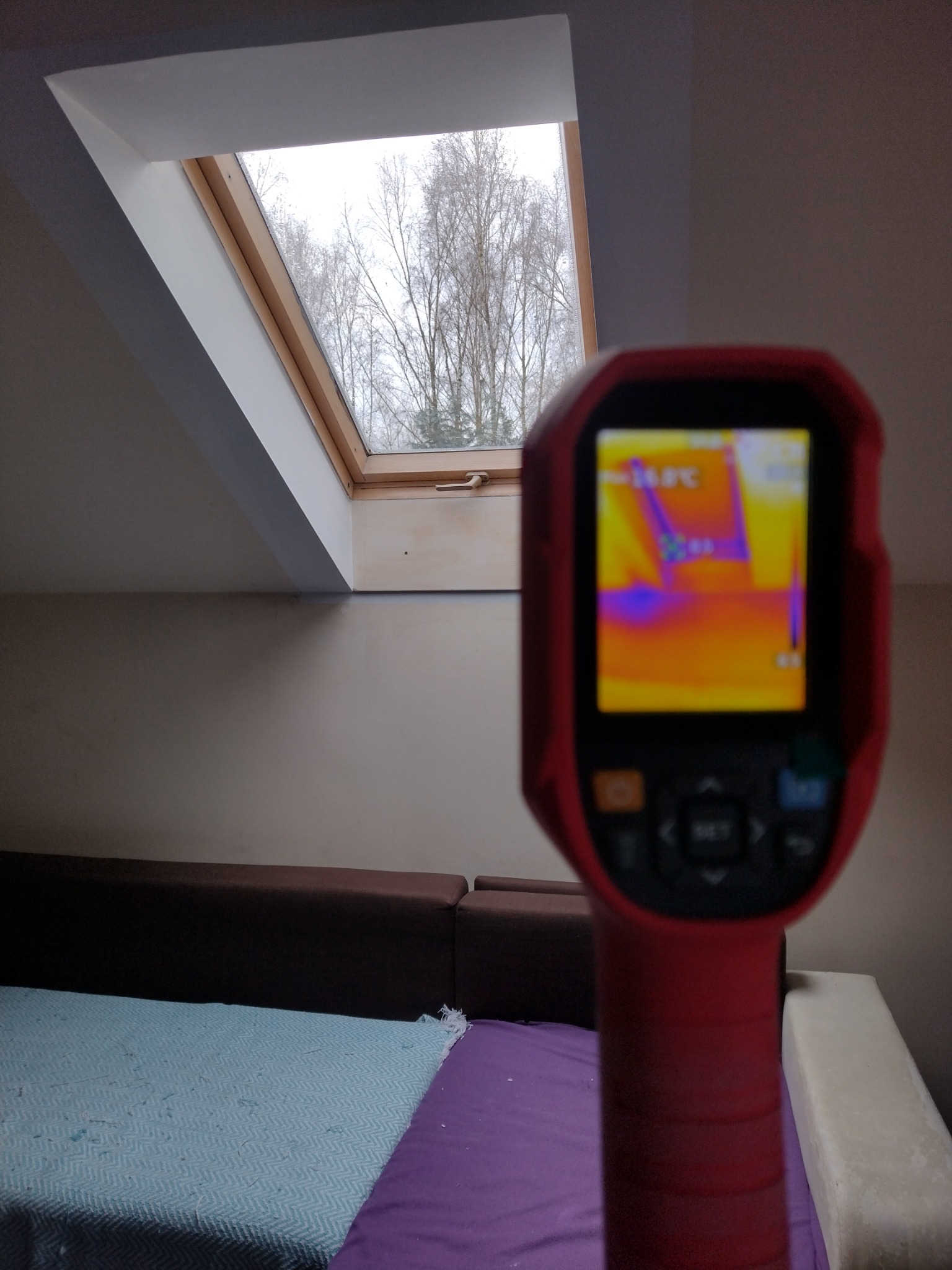 Kamera termowizyjna skierowana na okno dachowe, ukazująca rozkład temperatur na powierzchni poddasza.