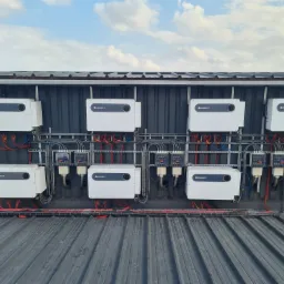 Rząd paneli fotowoltaicznych marki Growatt zamontowanych na metalowej konstrukcji, widoczne przewody i zabezpieczenia elektryczne.