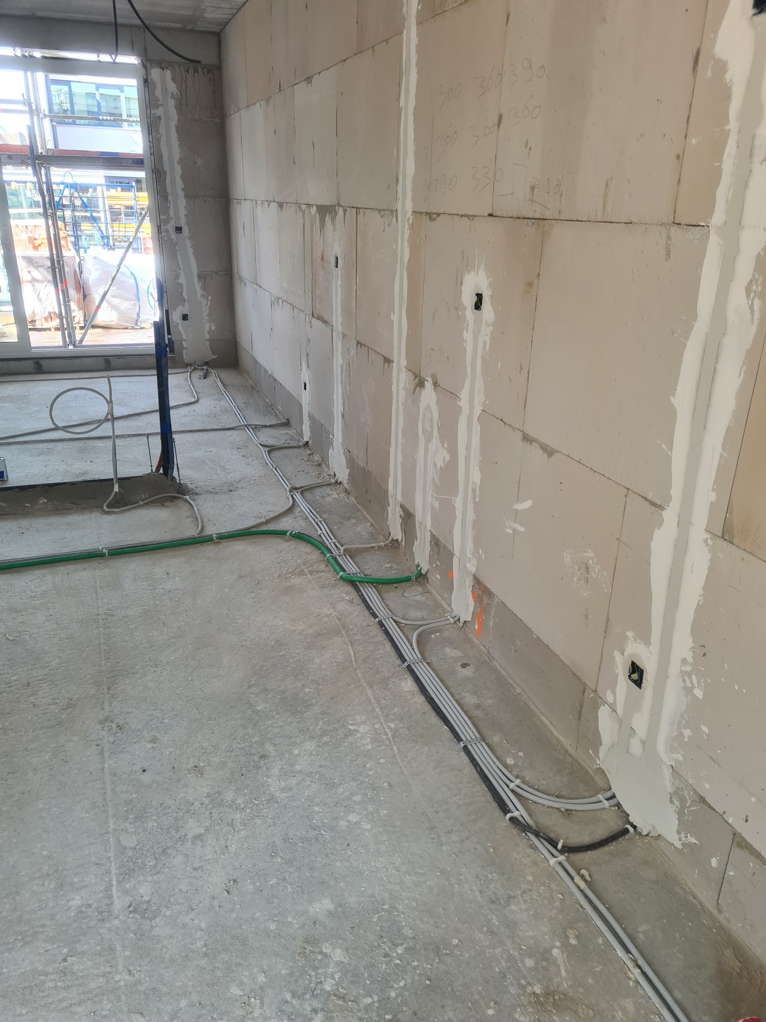 Wewnętrzne okablowanie elektryczne w rurkach ochronnych, częściowo zamaskowane w ścianie z betonu komórkowego, widoczne otwory pod gniazdka.