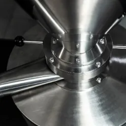 Szczegółowe ujęcie polerowanej, nierdzewnej maszyny z zaworem i elementami sterującymi, widoczne śruby mocujące i spawane łączenia.