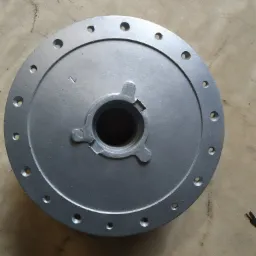 Szara, okrągła piasta koła z otworami na śruby, leżąca na drewnianej powierzchni. Widoczny centralny otwór z trzema wypustkami.