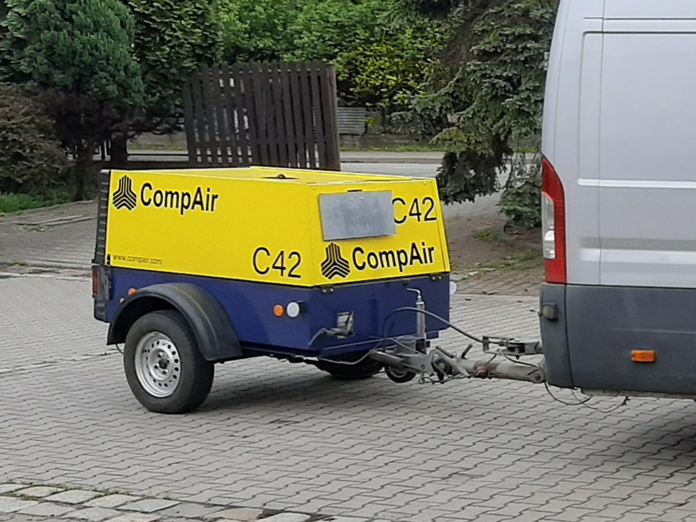 Przyczepa z kompresorem CompAir C42, zaparkowana za samochodem dostawczym na kostce brukowej.
