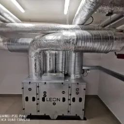 Centrala wentylacyjna LEON X z izolowanymi przewodami w pomieszczeniu technicznym, widoczna instalacja elektryczna.
