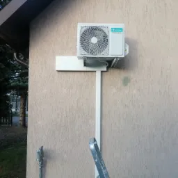 Zewnętrzna jednostka klimatyzacji Hisense zamontowana na elewacji domu z widoczną instalacją i fragmentem drabiny.