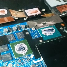 MAC-IT - Otwarta obudowa laptopa z widoczną płytą główną, procesorami pokrytymi świeżą pastą termoprzewodzącą i elementami układu chłodzenia. Widoczne moduły pamięci Samsung.