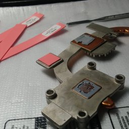 MAC-IT - Metalowy radiator z pozostałościami pasty termoprzewodzącej i nowymi termopadami, przygotowany do montażu w laptopie, obok leżą narzędzia i etykiety z grubością termopadów
