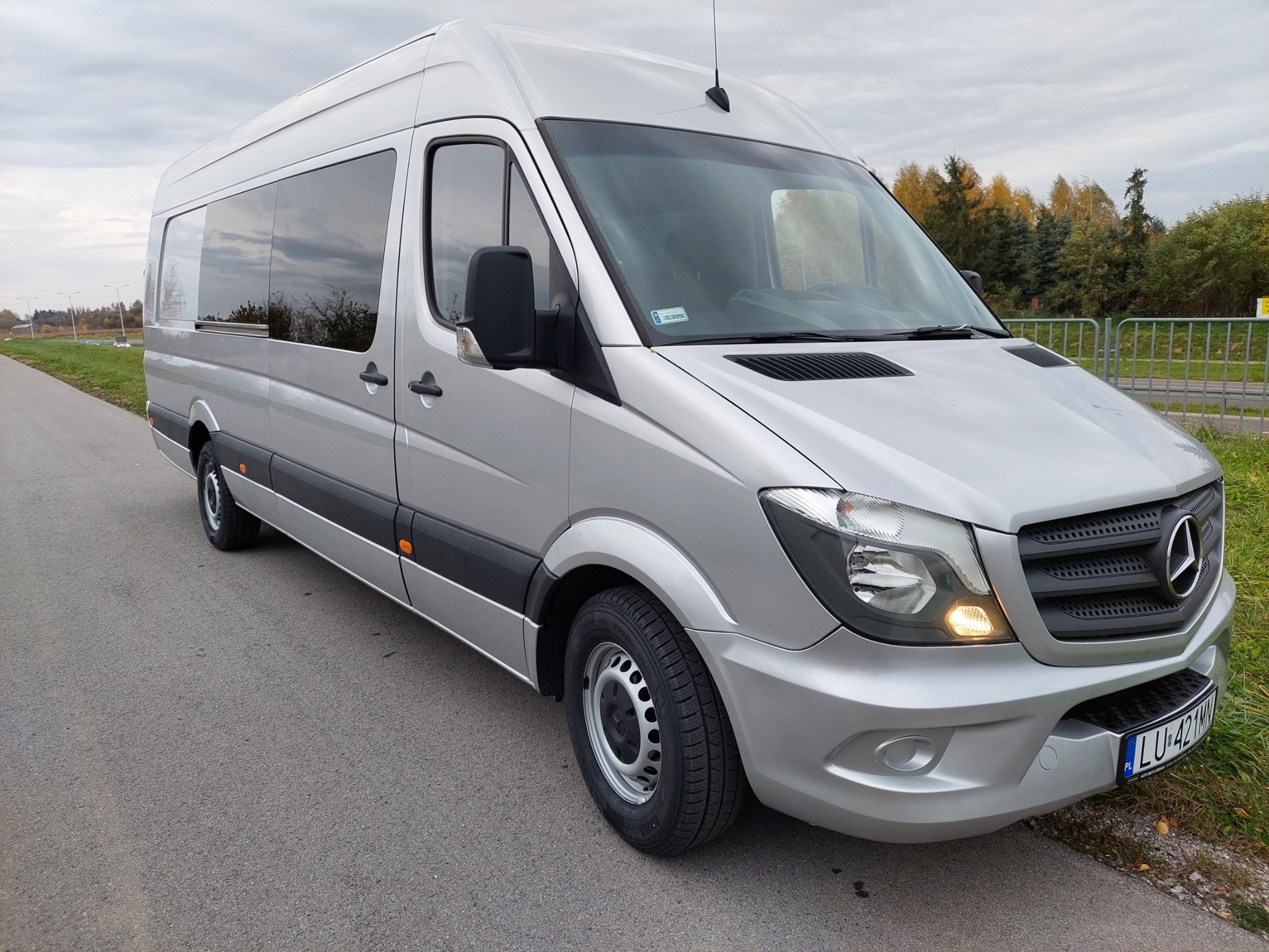 Srebrny bus Mercedes Sprinter na poboczu drogi, widok z przodu z lekkiego ukosa, widoczne tablice rejestracyjne LU 421KN.