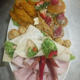 Kamil Bilski - Elegancki, biały talerz z wyszukanymi przekąskami: mini tortille, burgery, roladki i wędliny, tworząc apetyczną kompozycję cateringową.