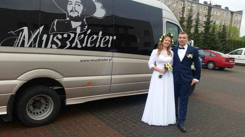 Para młoda pozuje przed srebrnym busem z grafiką stylizowaną na Che Guevarę i napisem 'Muszkieter' oraz adresem strony internetowej.