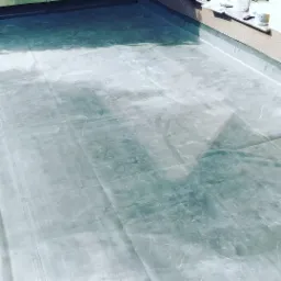 Hydroizolacja płaskiego dachu pokryta folią, widoczne zgrzewy i detale wykończeniowe przy krawędzi dachu.