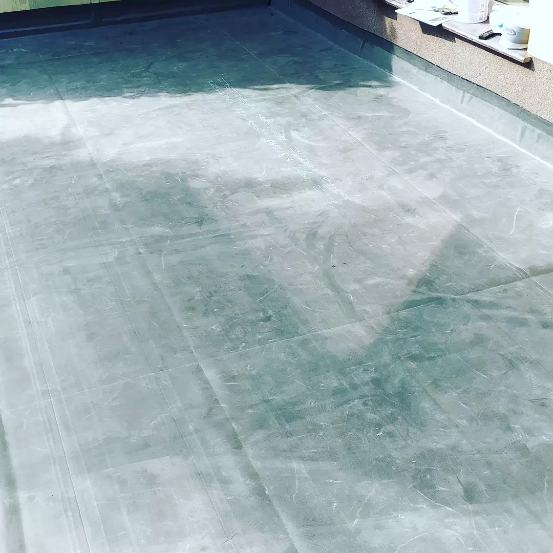 Hydroizolacja płaskiego dachu pokryta folią, widoczne zgrzewy i detale wykończeniowe przy krawędzi dachu.