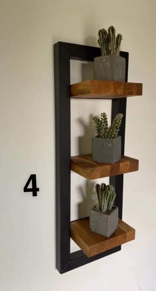 Półka ścienna z trzema drewnianymi poziomami w czarnej, metalowej ramie, na których stoją małe sukulenty w szarych, betonowych doniczkach; na ścianie widoczna czarna cyfra 4.