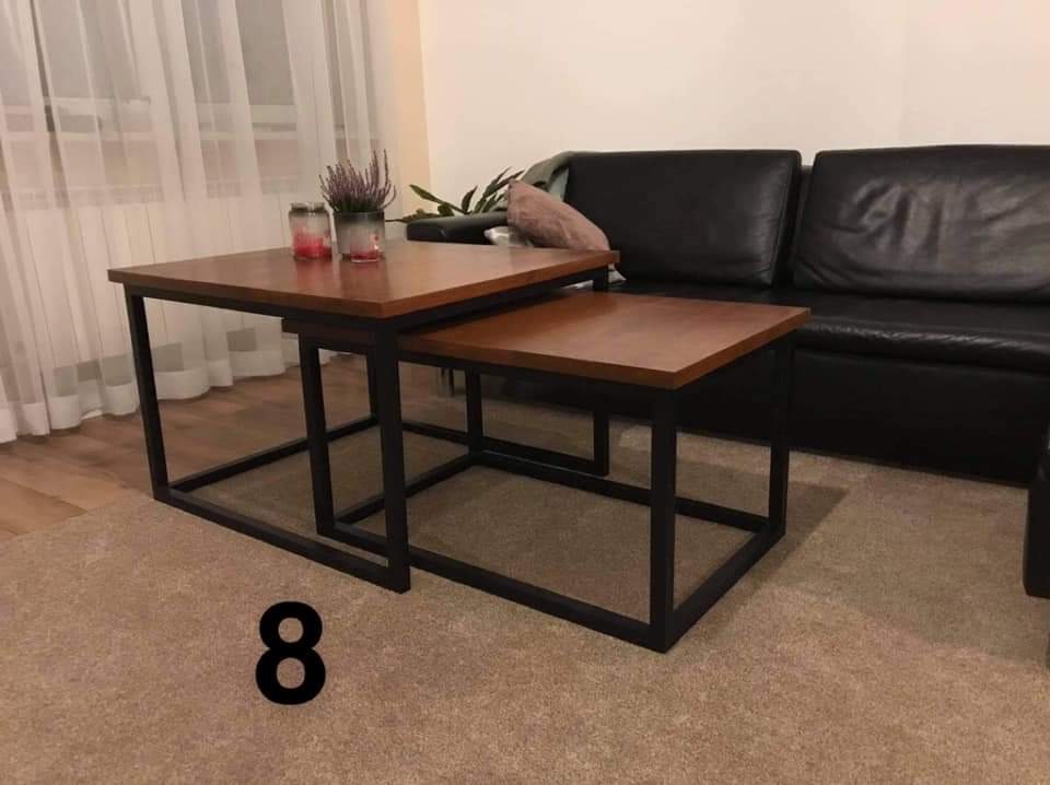 Dwa stoliki kawowe z drewnianymi blatami i czarnymi metalowymi nogami, ustawione jeden pod drugim, na tle skórzanej kanapy i zasłon okiennych.