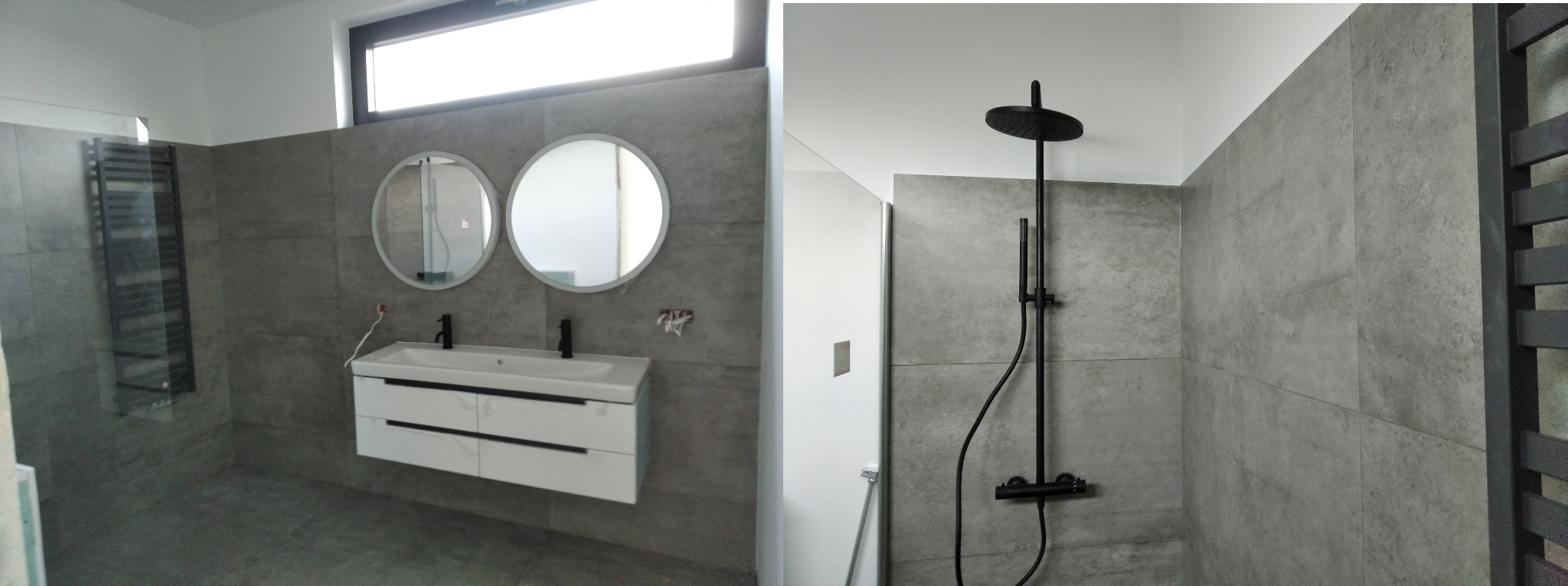 Nowoczesna łazienka z szarymi płytkami, białymi szafkami pod umywalką z czarną armaturą, dwoma okrągłymi lustrami, czarnym grzejnikiem drabinkowym oraz czarnym zestawem prysznicowym typu deszczownica.