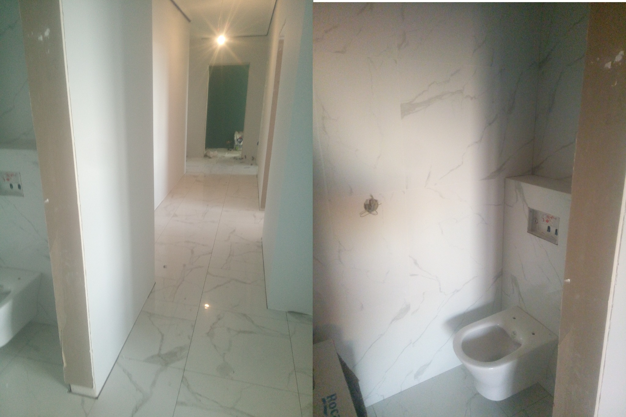 Wnętrze łazienki w trakcie prac wykończeniowych: białe płytki imitujące marmur na ścianach i podłodze, zamontowana toaleta podtynkowa, widoczne instalacje elektryczne, surowa ściana działowa...