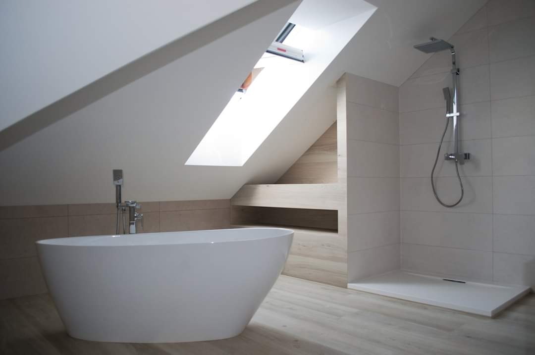Nowoczesna łazienka na poddaszu ze skośnym sufitem, wolnostojąca wanna owalna, prysznic typu walk-in z deszczownicą i płytki w odcieniach beżu i bieli
