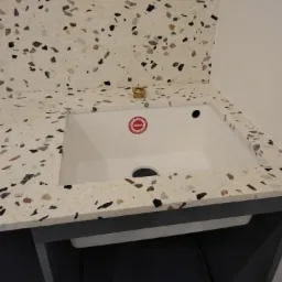 Biały zlew TEKA w blacie z konglomeratu o wzorze lastryko, widoczny otwór na baterię i fragment syfonu.