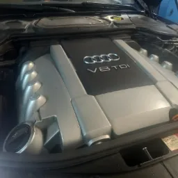 Silnik V8 TDI Audi z otwartą maską, widoczny korek wlewu oleju i naklejki informacyjne.