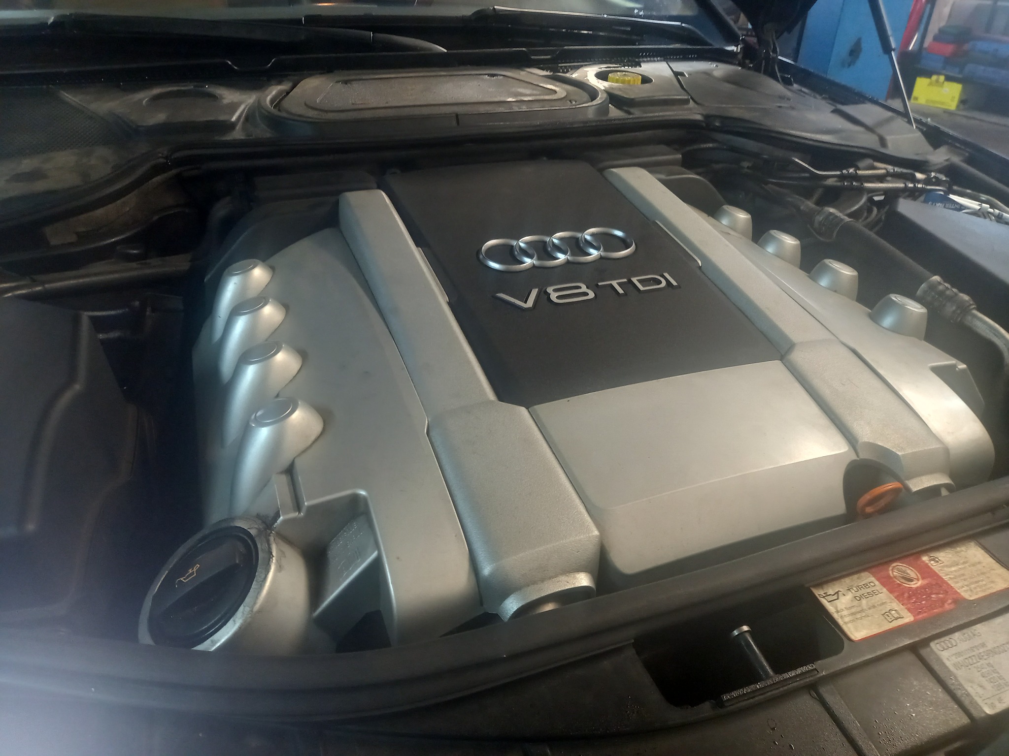 Silnik V8 TDI Audi z otwartą maską, widoczny korek wlewu oleju i naklejki informacyjne.