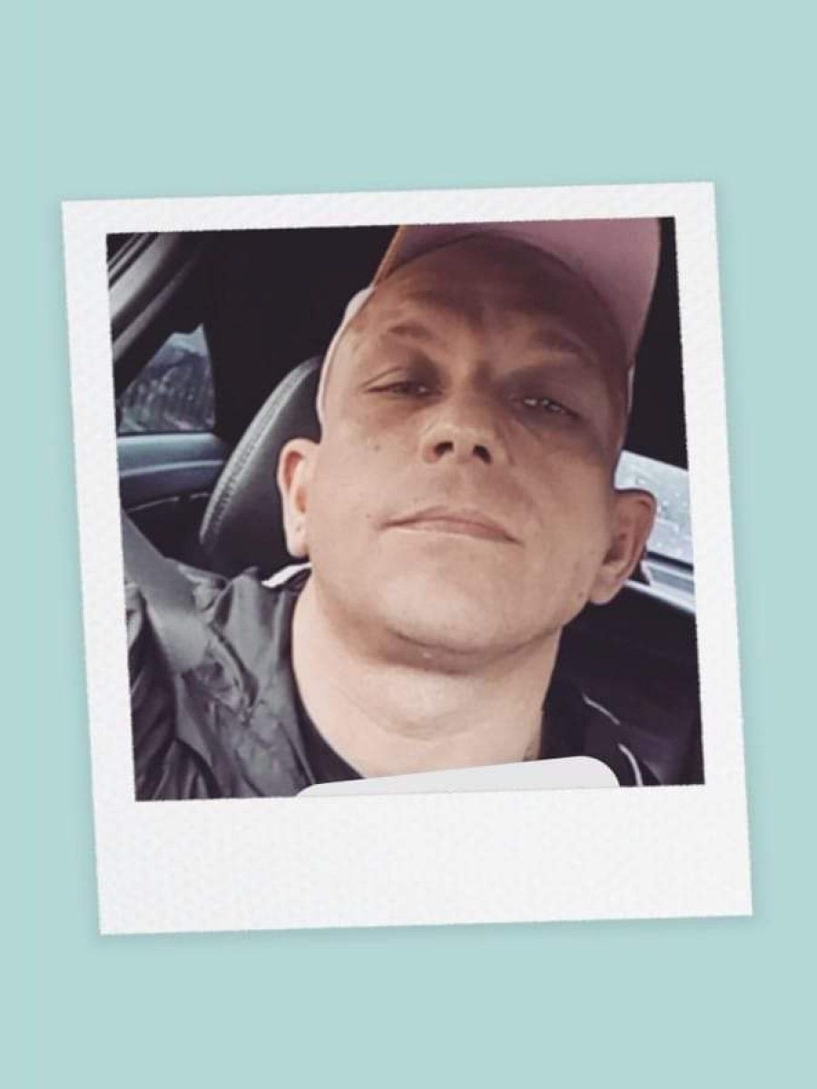 Portret mężczyzny w różowej czapce z daszkiem, siedzącego w samochodzie, zrobiony w stylu polaroid.