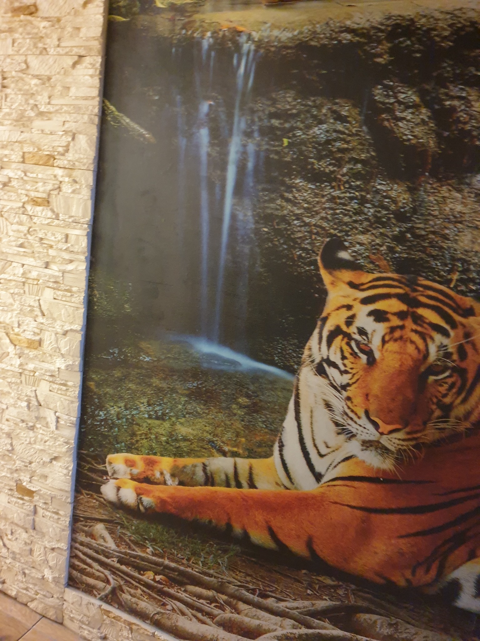Tapeta z motywem tygrysa i wodospadu, przylegająca do ściany z dekoracyjnej cegły w Przeworsku.