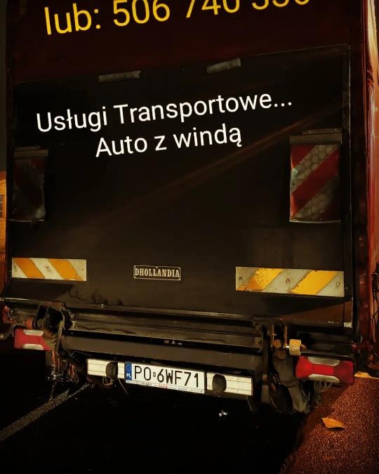 Tył samochodu dostawczego z napisem 'Usługi Transportowe... Auto z windą' i numerem telefonu, widoczne światła i tablica rejestracyjna PO-6WF71.